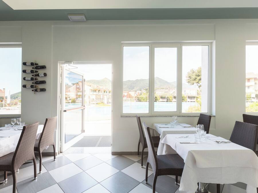 A dining area with tables set for two, chairs, and a wall-mounted wine rack.