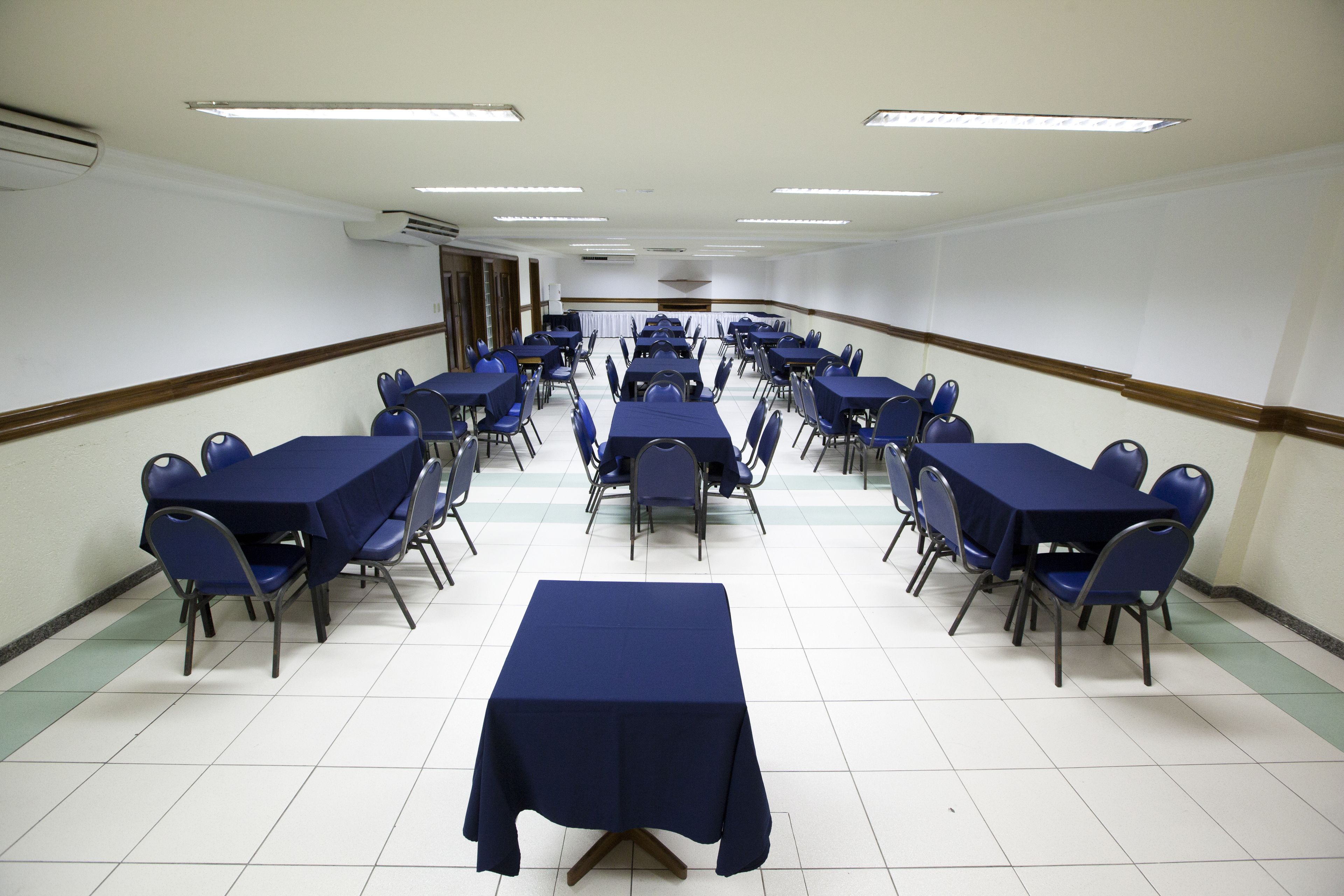 Una sala conferenze con diversi tavoli e sedie disposti in file.