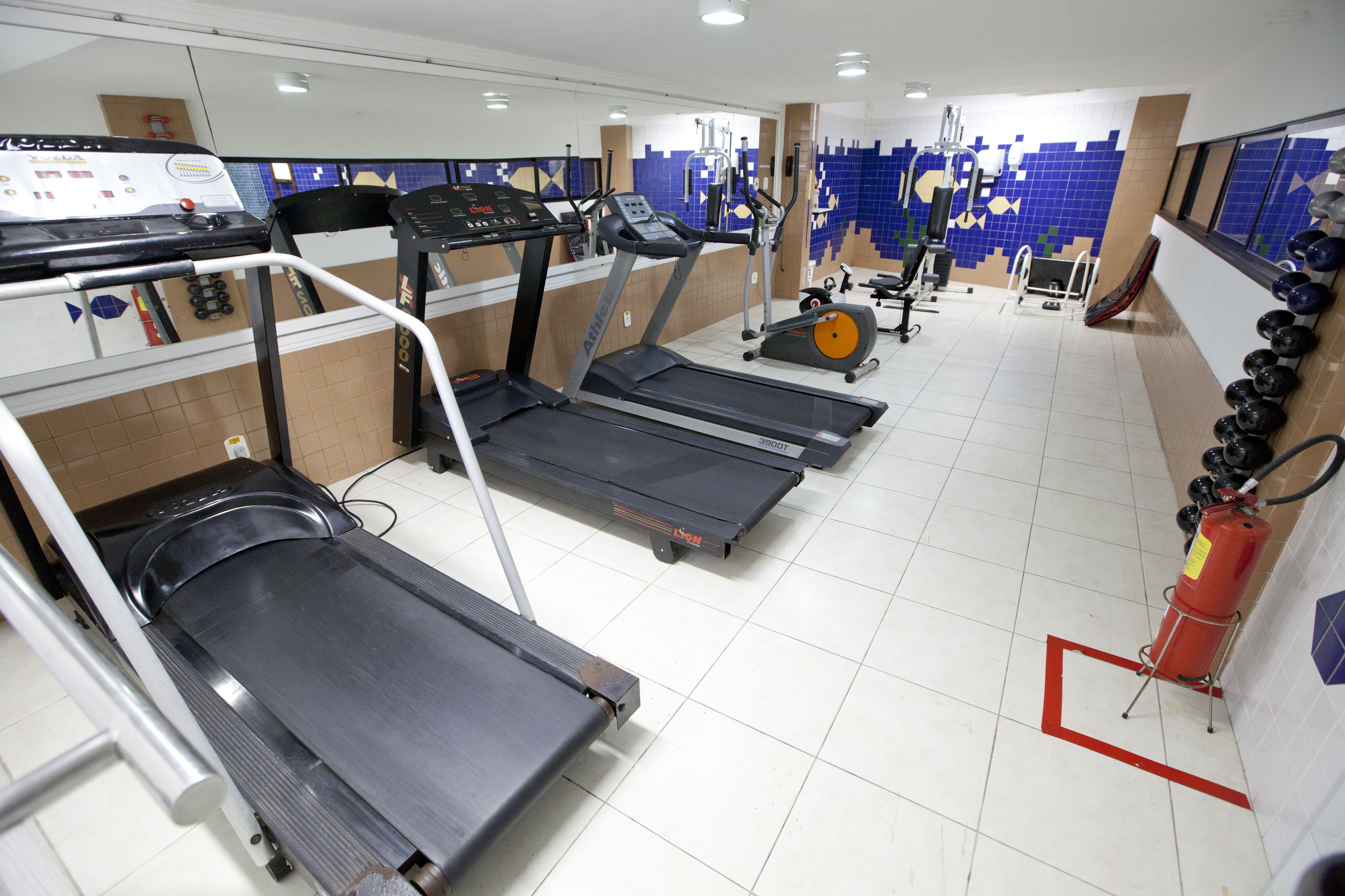 A gym with treadmills, exercise bikes, and a fire extinguisher.