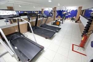A gym with treadmills, exercise bikes, and a fire extinguisher.
