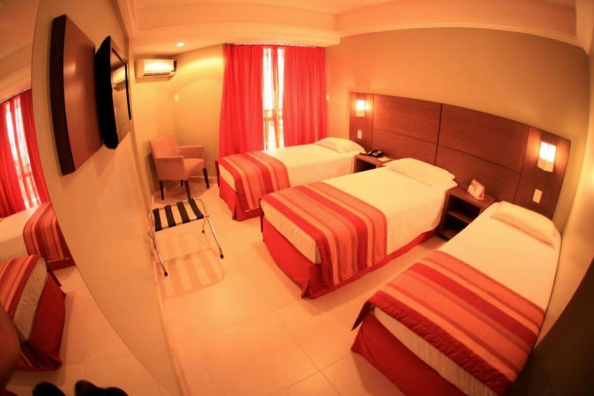 A hotel room with two beds, a desk, and a chair.