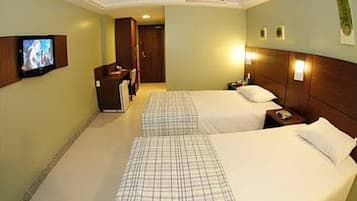 A hotel room with two beds, a TV, a desk, and a chair.