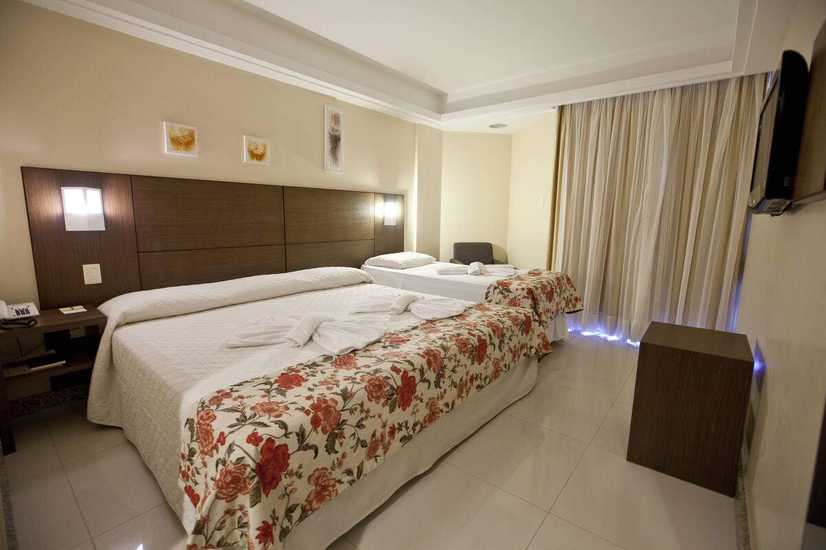 A hotel room with two beds, a flat-screen TV, a desk, and a chair.