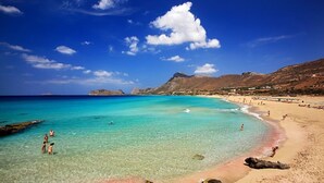 A beach with clear turquoise water, rocky outcrops, and a mountainous backdrop. - Maria Villas (Kissamos)