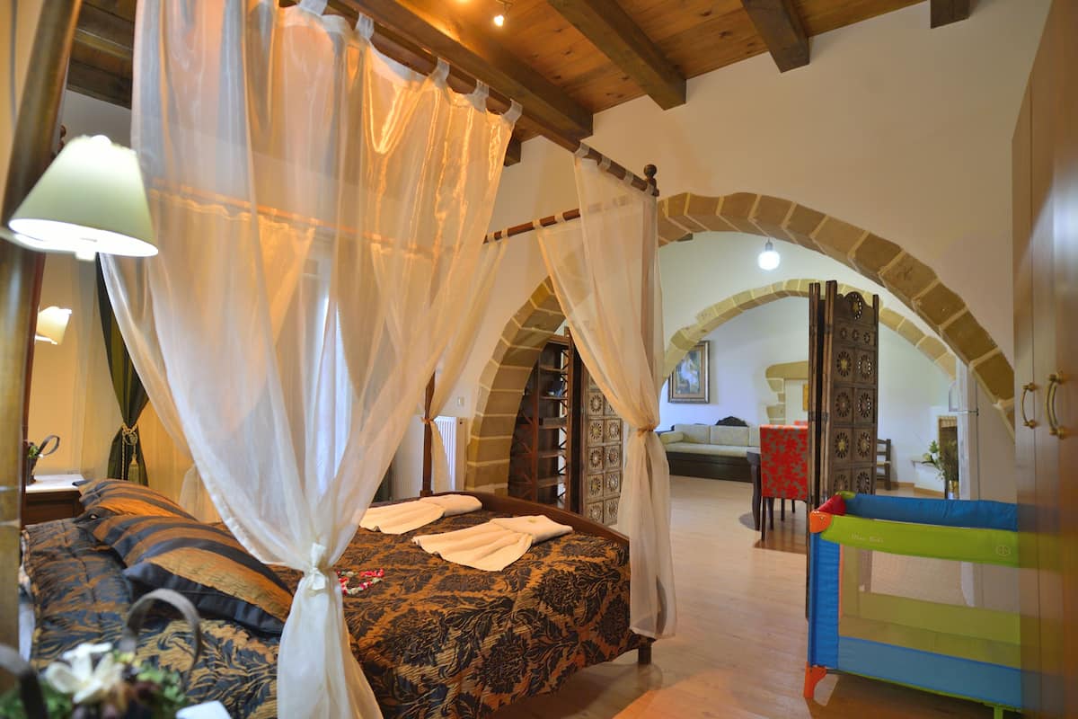 A bedroom with a four-poster bed, a canopy, and a small playpen.