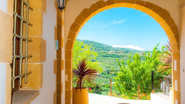 An arched doorway leading to a balcony with a view of a green landscape and hills. - Maria Villas (Kissamos)