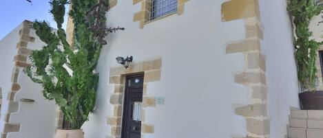 Un edificio con fachada blanca y detalles de piedra beige, que incluye una ventana y una puerta.