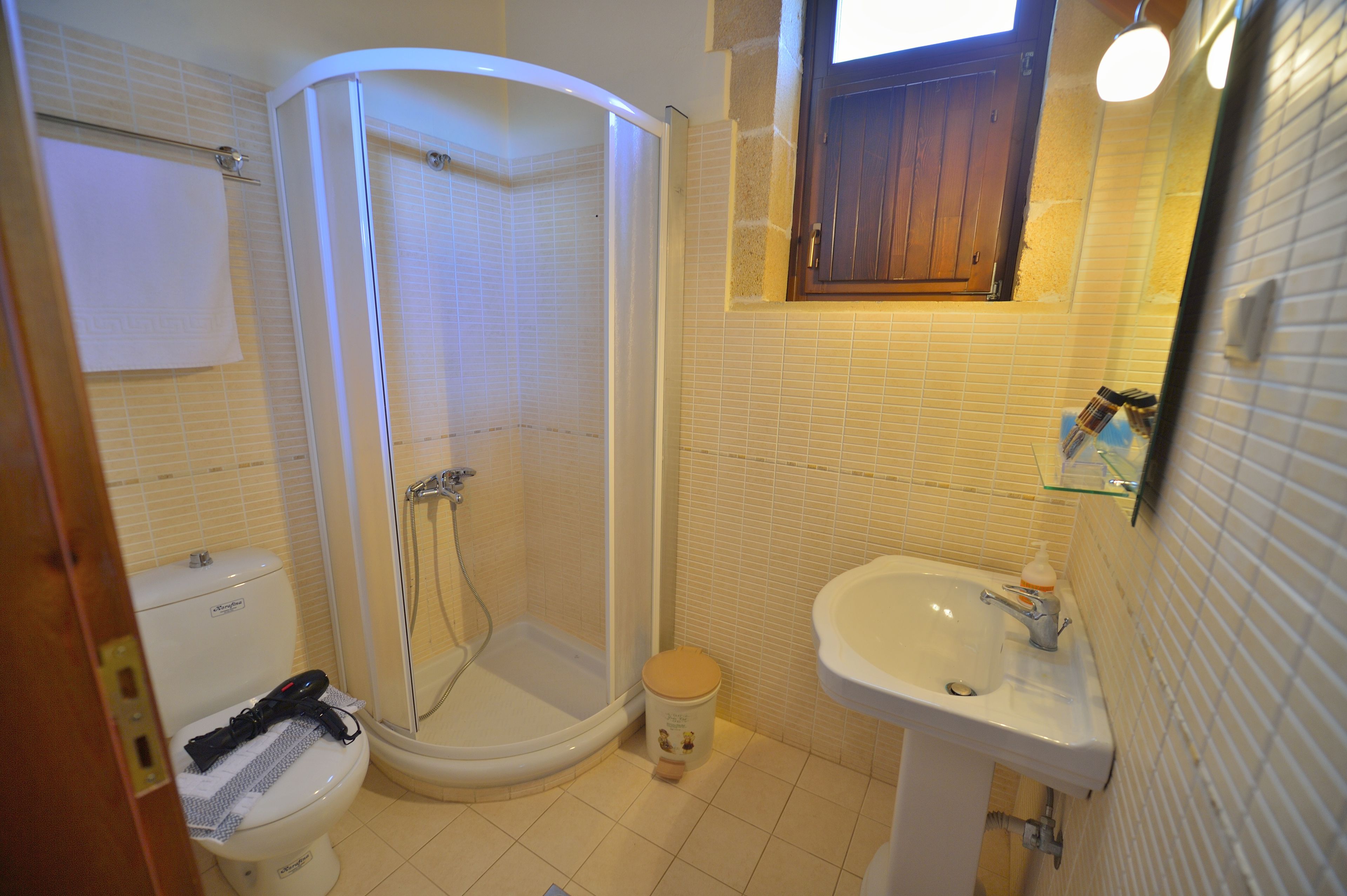 A bathroom with a toilet, shower, and sink.