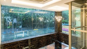 A modern interior with a large glass window overlooking a green outdoor area. - LYNQ CICO (Kolkata)