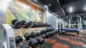 A gym with rows of dumbbells, exercise equipment, and a patterned carpet. - LYNQ CICO (Kolkata)