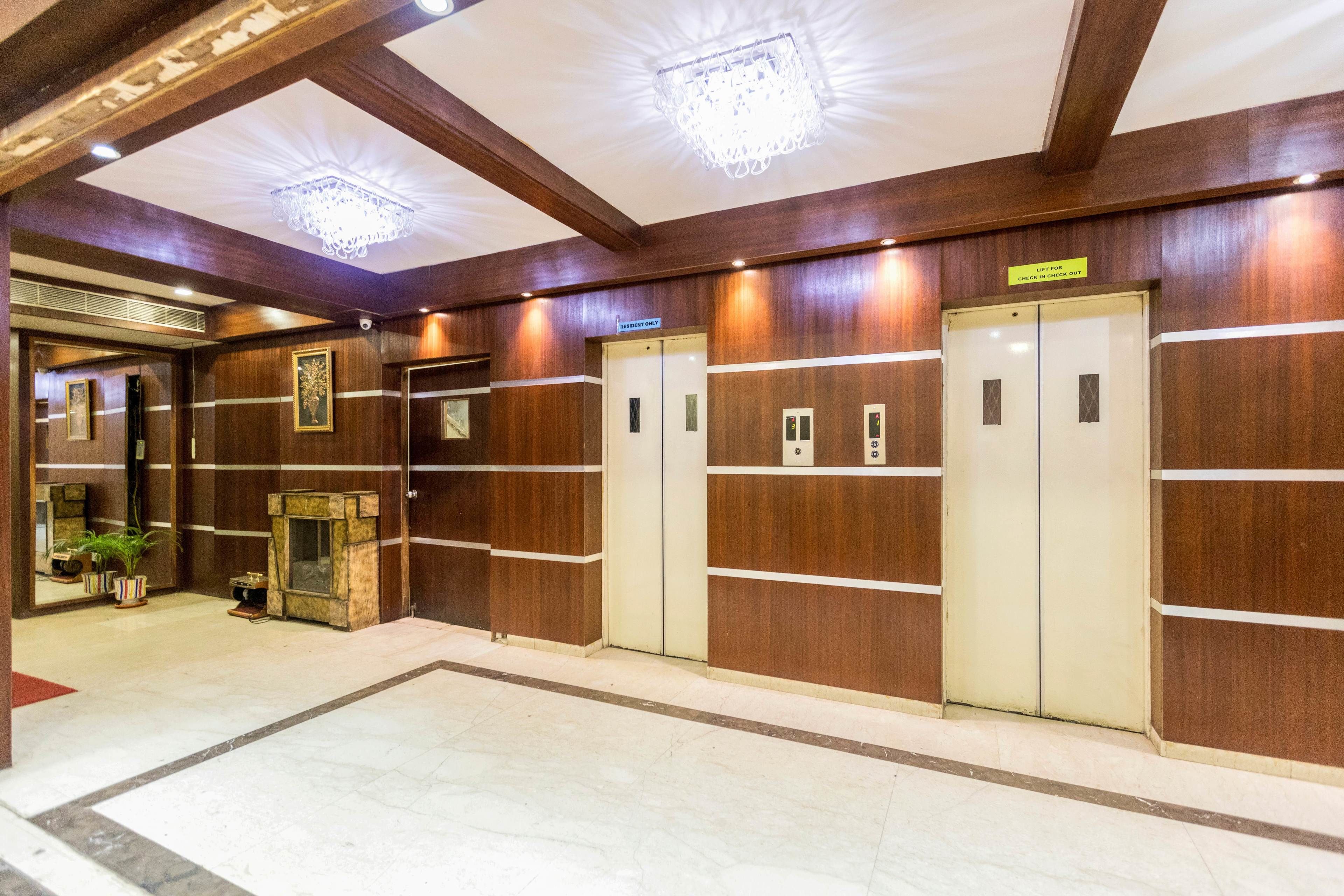 A hotel lobby with wooden paneling, a marble floor, and a chandelier.