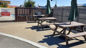 An outdoor patio area with picnic tables and umbrellas, a fenced pool area, and a McDonald's sign in the background.