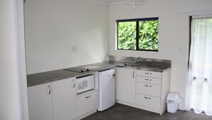 A compact kitchen with white cabinets, a microwave, a dishwasher, and a sink.