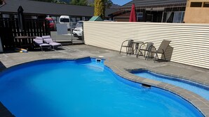 A swimming pool with a tiled edge, surrounded by a wooden fence and a concrete deck.