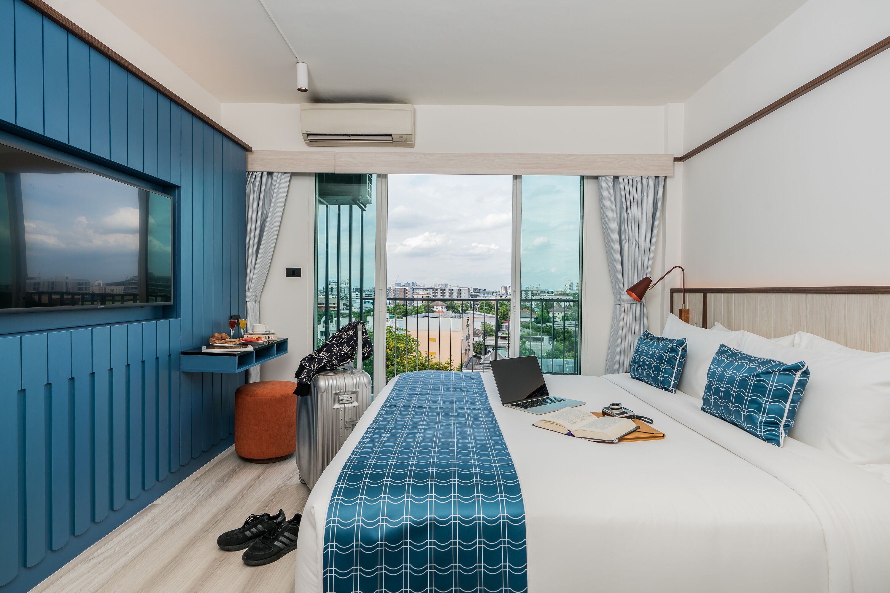 Une chambre d’hôtel moderne avec un grand lit, un ordinateur portable et une vue sur la ville.