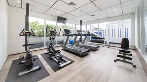 Un gimnasio moderno con cintas de correr, elípticas y pesas libres.
