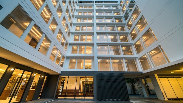 Un edificio moderno con varios pisos, ventanas amplias y una entrada central con un reloj.