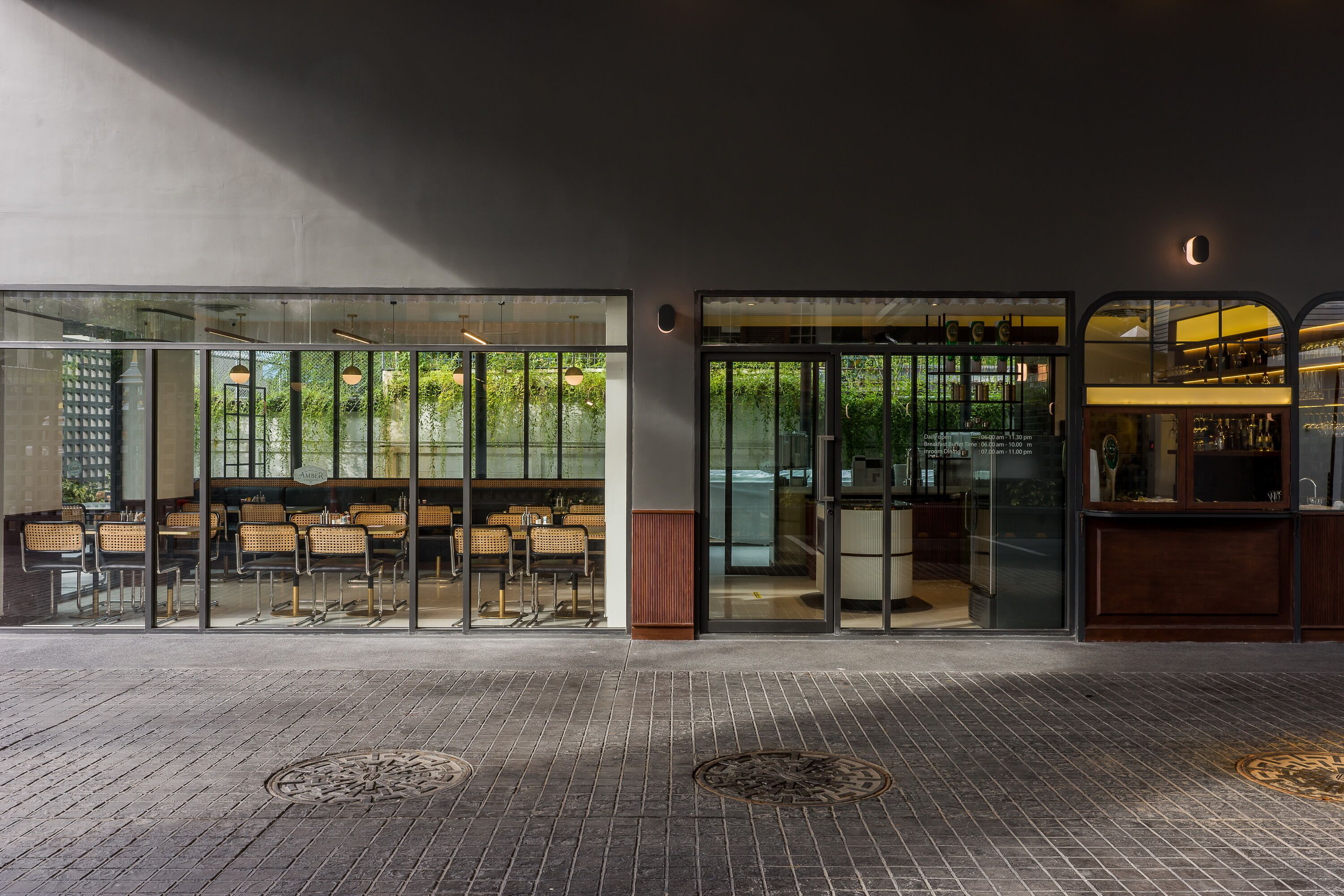 A restaurant with outdoor seating, large windows, and a brick-paved entrance.