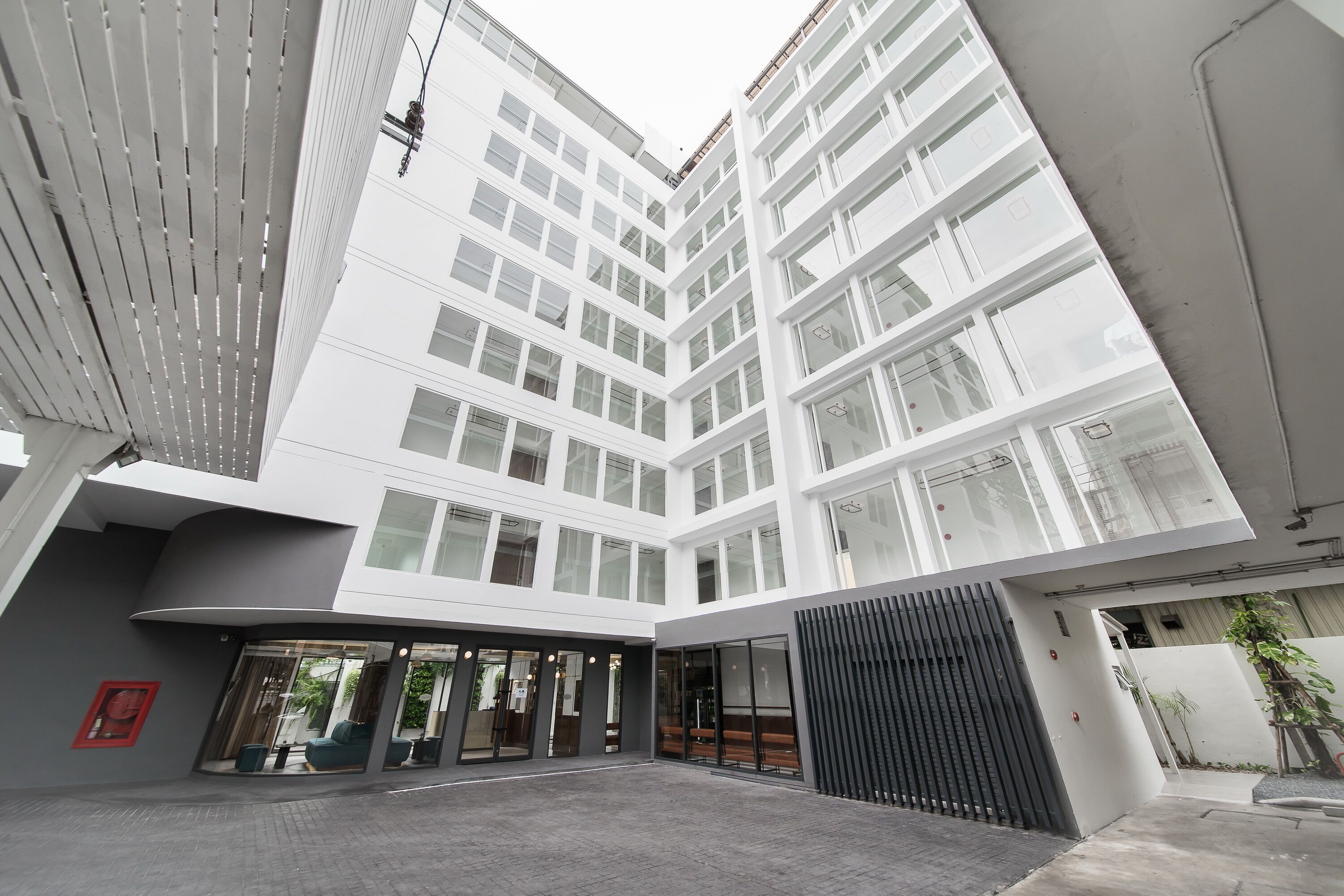 A modern building with a courtyard, large windows, and a covered entrance area.