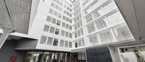 A modern building with a courtyard, large windows, and a covered entrance area.