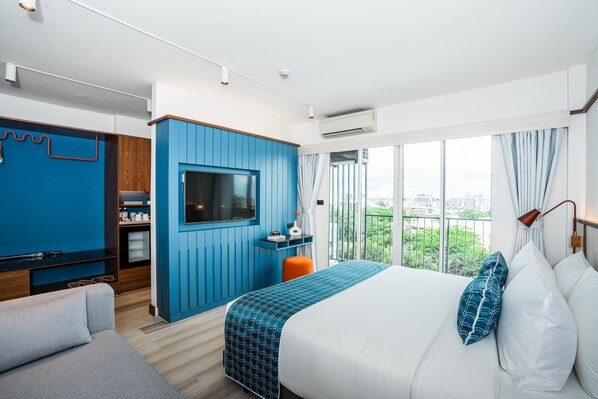 Une chambre d’hôtel moderne dotée d’un grand lit, d’une télévision, d’un bureau et offrant une vue sur la ville.