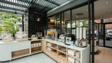 Un café moderne avec un comptoir où sont exposées différentes machines à café et une vitrine réfrigérée.