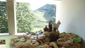 A buffet table with various cheeses, fruits, and pastries, set against a backdrop of a scenic outdoor view. - Solar Quinta da Portela (Santa Marta de Penaguião)