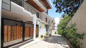 A narrow street with a modern two-story building, a gated entrance, and a clear sky.