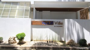 A modern building with a sign reading "Westcliff Villa" by Bluevies. It features a balcony with metal railings and a white exterior.