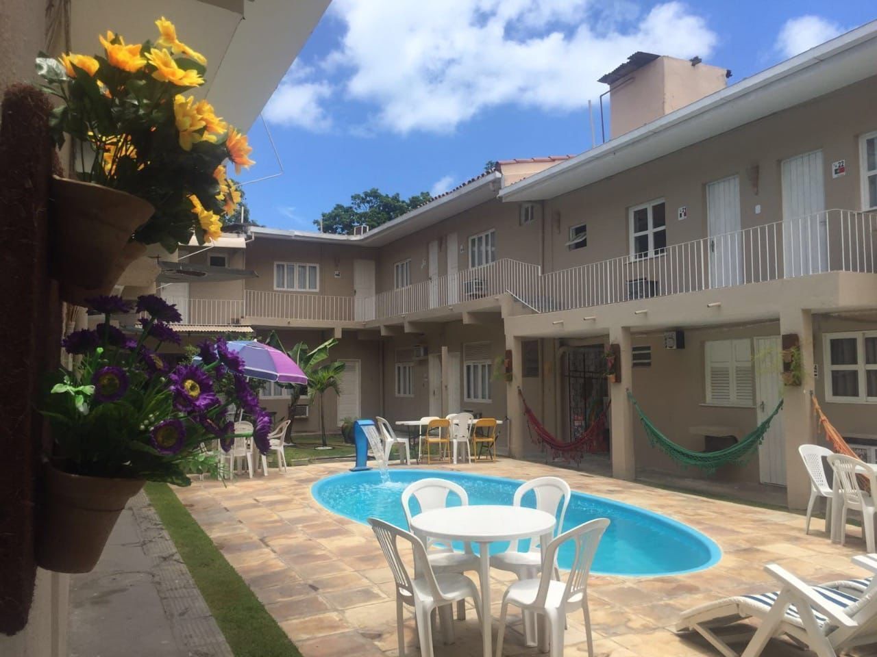 A courtyard with a swimming pool, outdoor seating, and a hanging flower pot.