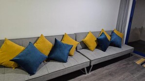 A grey sofa with alternating yellow and blue cushions. - Andean Dreams Hotel (Cusco)
