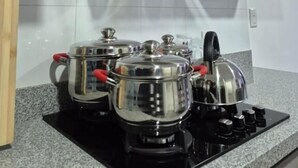 A kitchen with a gas stove, pots, and a modern range hood. - Andean Dreams Hotel (Cusco)