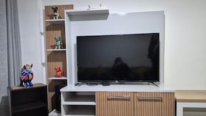 A modern living room with a large flat-screen TV mounted on a white entertainment unit. - Andean Dreams Hotel (Cusco)