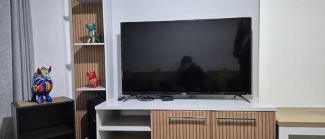 Una sala moderna con un televisor de pantalla plana grande montado en un mueble blanco.