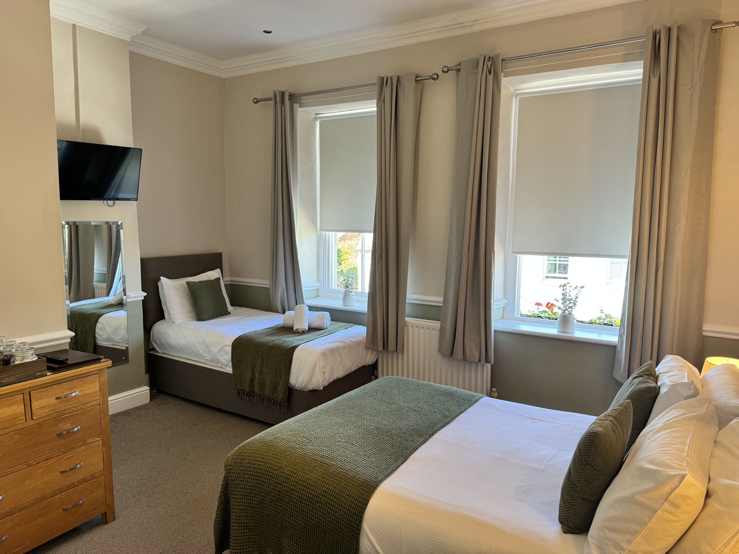 Een hotelkamer met twee bedden, een televisie, een dressoir en een raam met gordijnen.