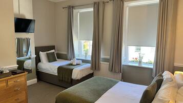 Een hotelkamer met twee bedden, een televisie, een dressoir en een raam met gordijnen.