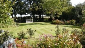 A well-maintained garden with a lawn, various shrubs, and trees.