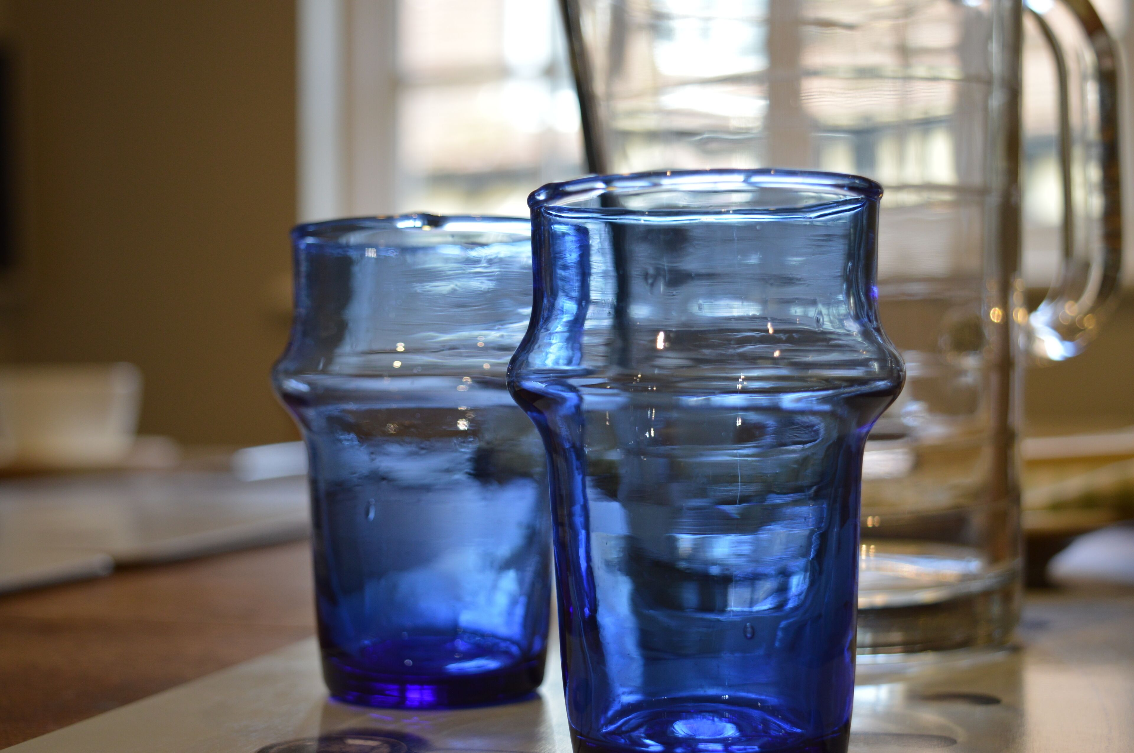 Two blue glass pitchers on a table.
