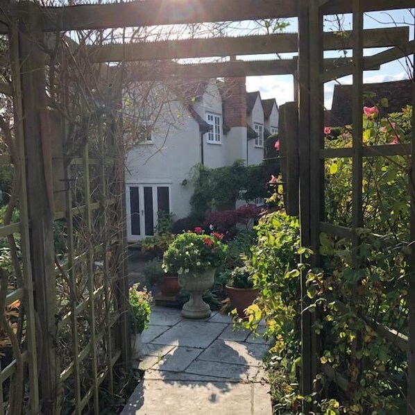 A wooden arbor leading to a garden with potted plants and a pathway.