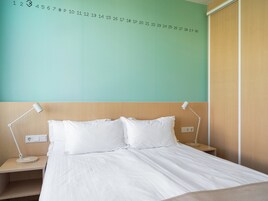 Una habitación de hotel con una cama, dos mesitas de noche y una pared con números.