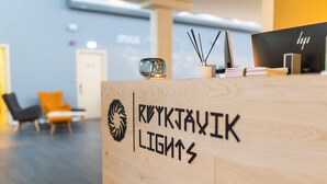 A reception desk with the name "ROYKJAVIK LIGHTS" and a logo. There are chairs and a table in the background. - Reykjavik Lights by Keahotels (Reykjavik)