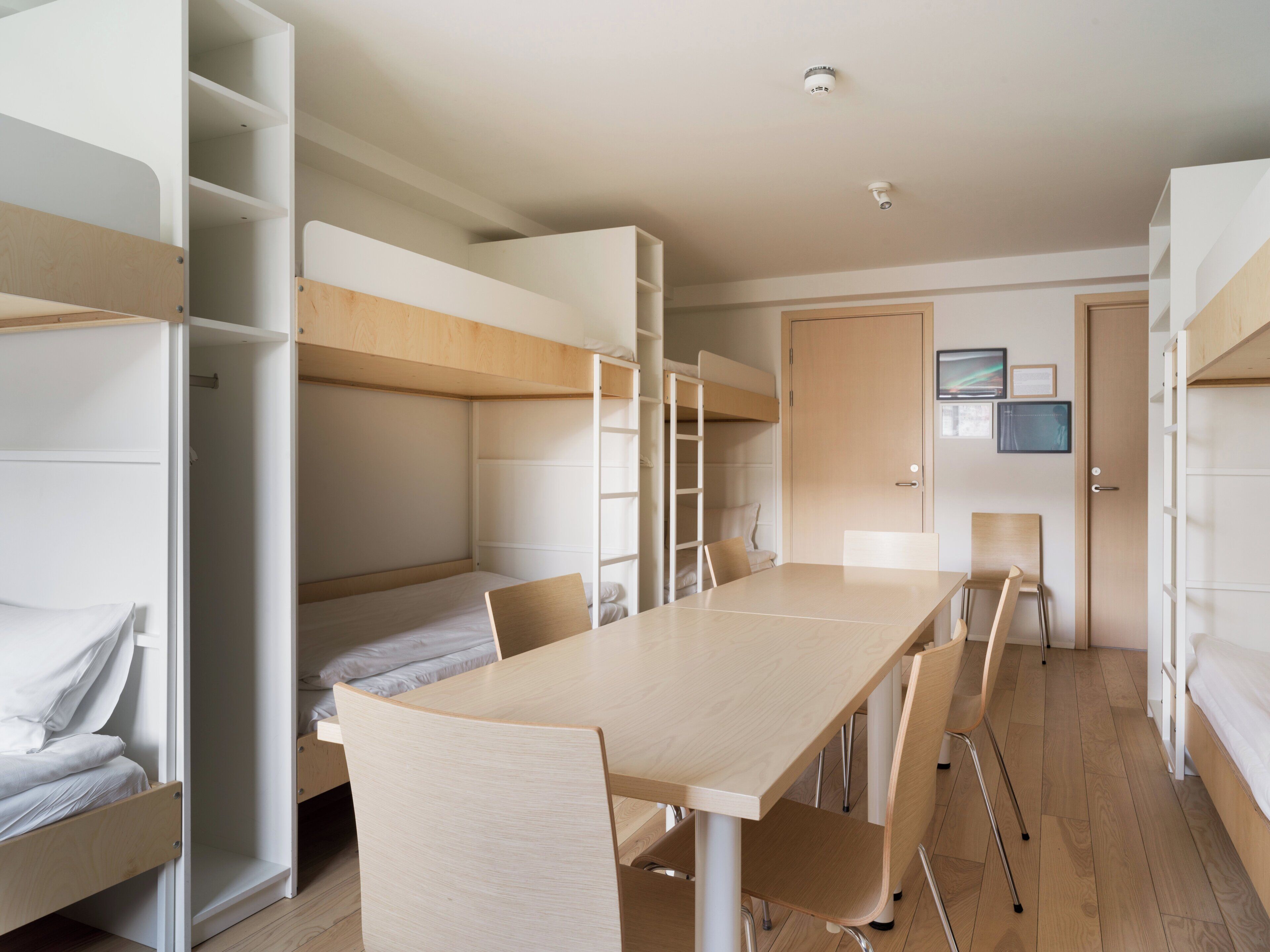 Un dormitorio con literas, un escritorio, sillas y una puerta.