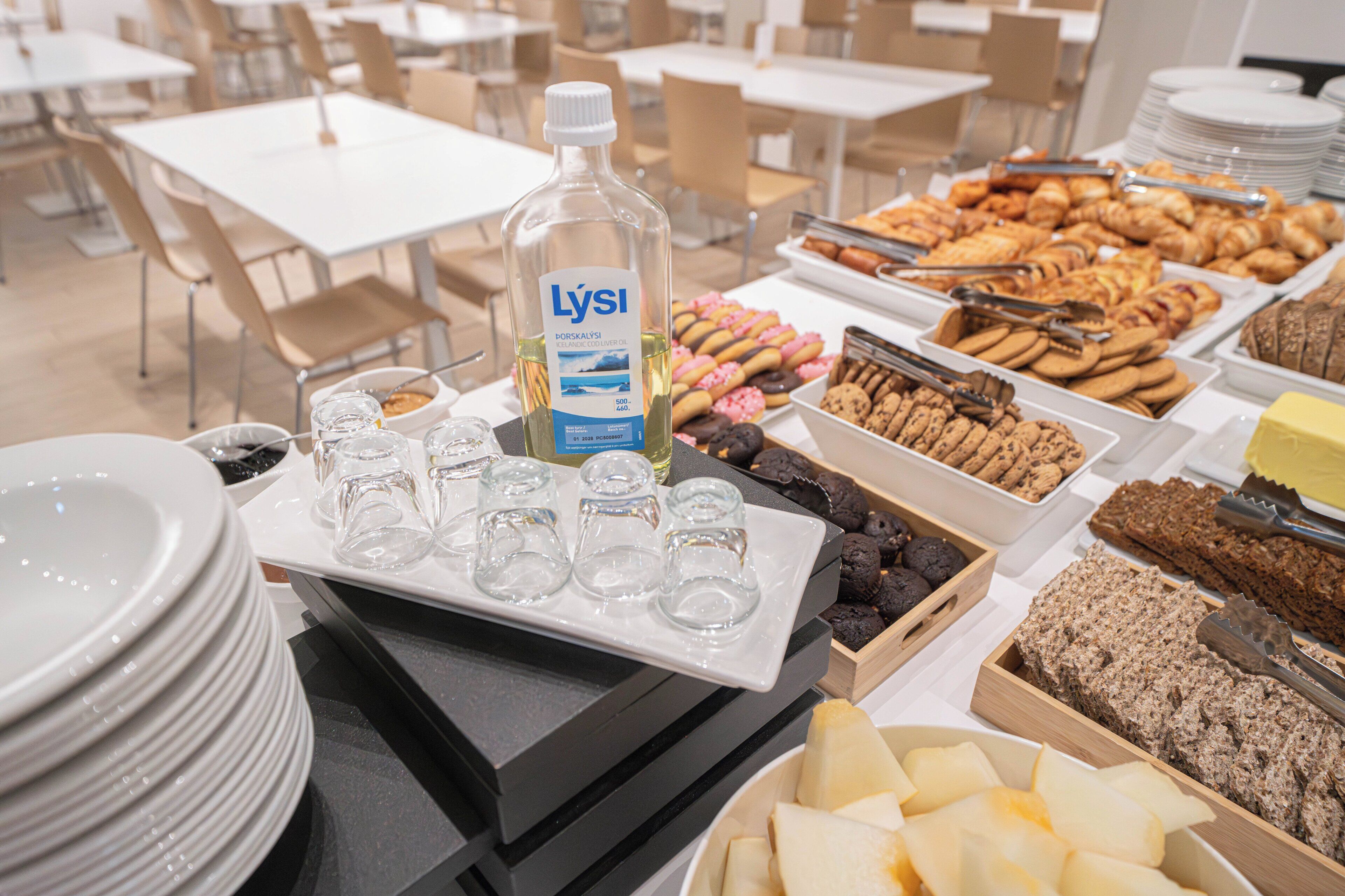 A buffet table with various food items, including pastries, cookies, and a bottle of Lysi oil.