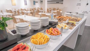 A buffet with various food items including watermelon, oranges, and bread. - Reykjavik Lights by Keahotels (Reykjavik)