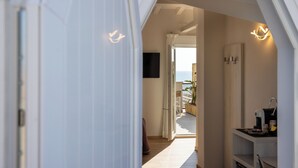 A hallway with a view to a balcony, a flat-screen TV mounted on the wall, and a coffee machine on a counter. - Hotel Biagi (Camaiore)