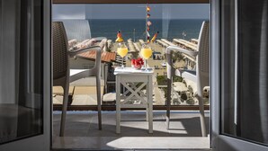 A balcony with a table, two chairs, and a view of the sea and beach. - Hotel Biagi (Camaiore)