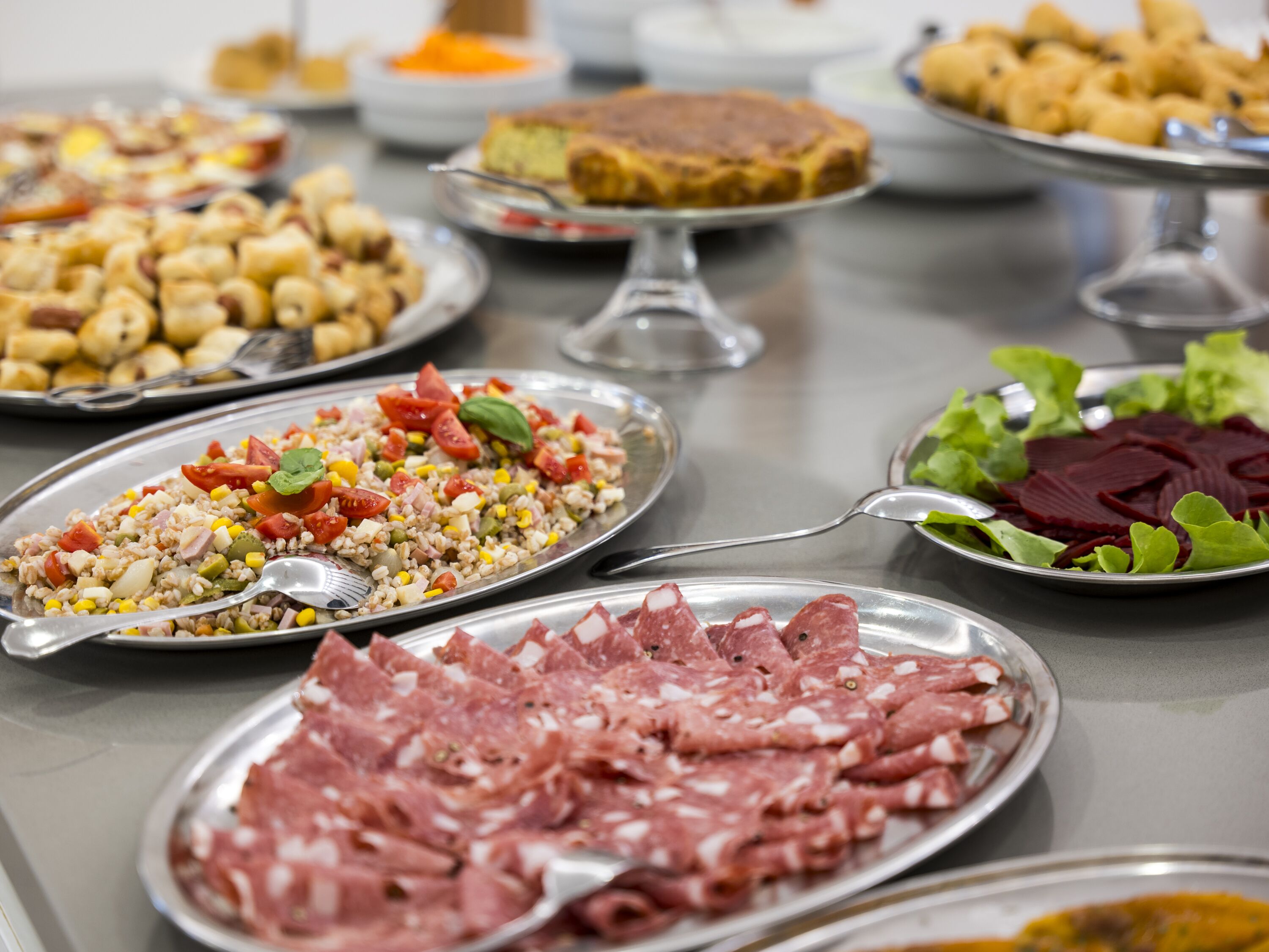 A buffet table with various dishes including salads, meats, and desserts.