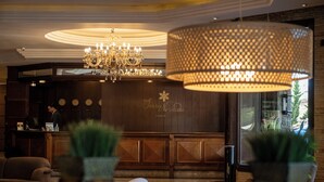 A hotel lobby with a chandelier, a reception desk, and potted plants. - Hotel Serra Nevada (Canela)