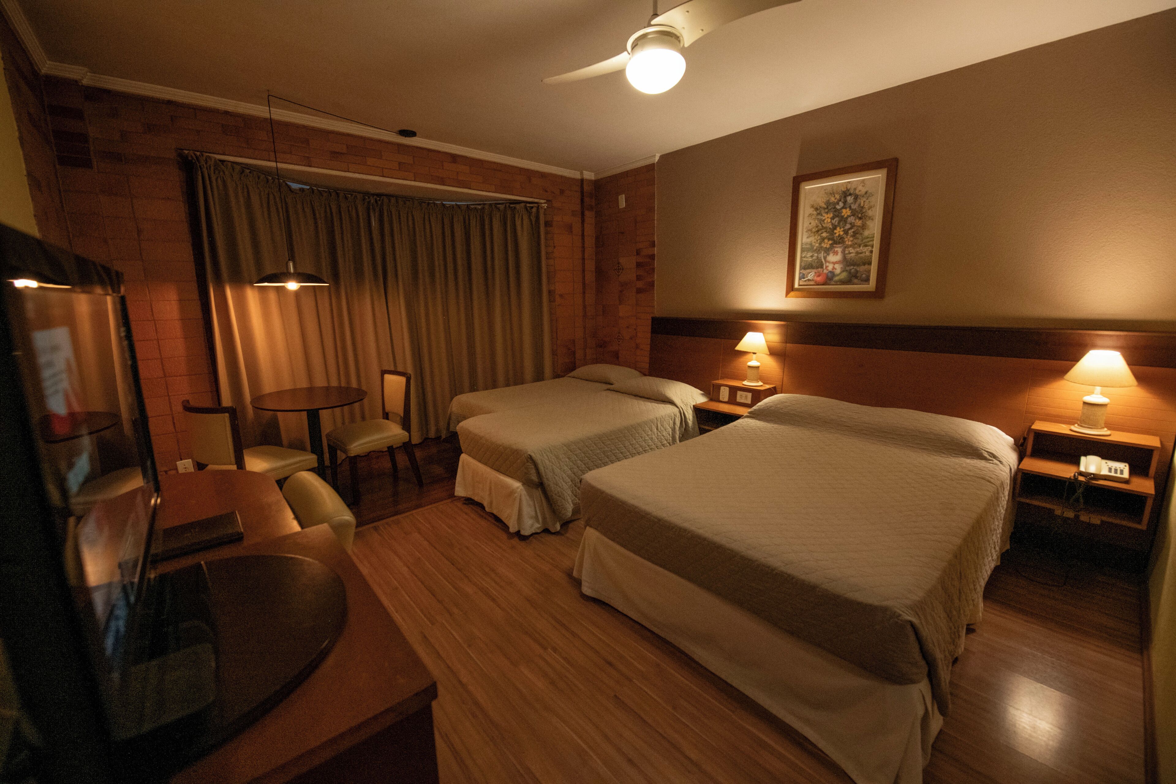 Habitación de hotel con dos camas, un escritorio, sillas y televisión.