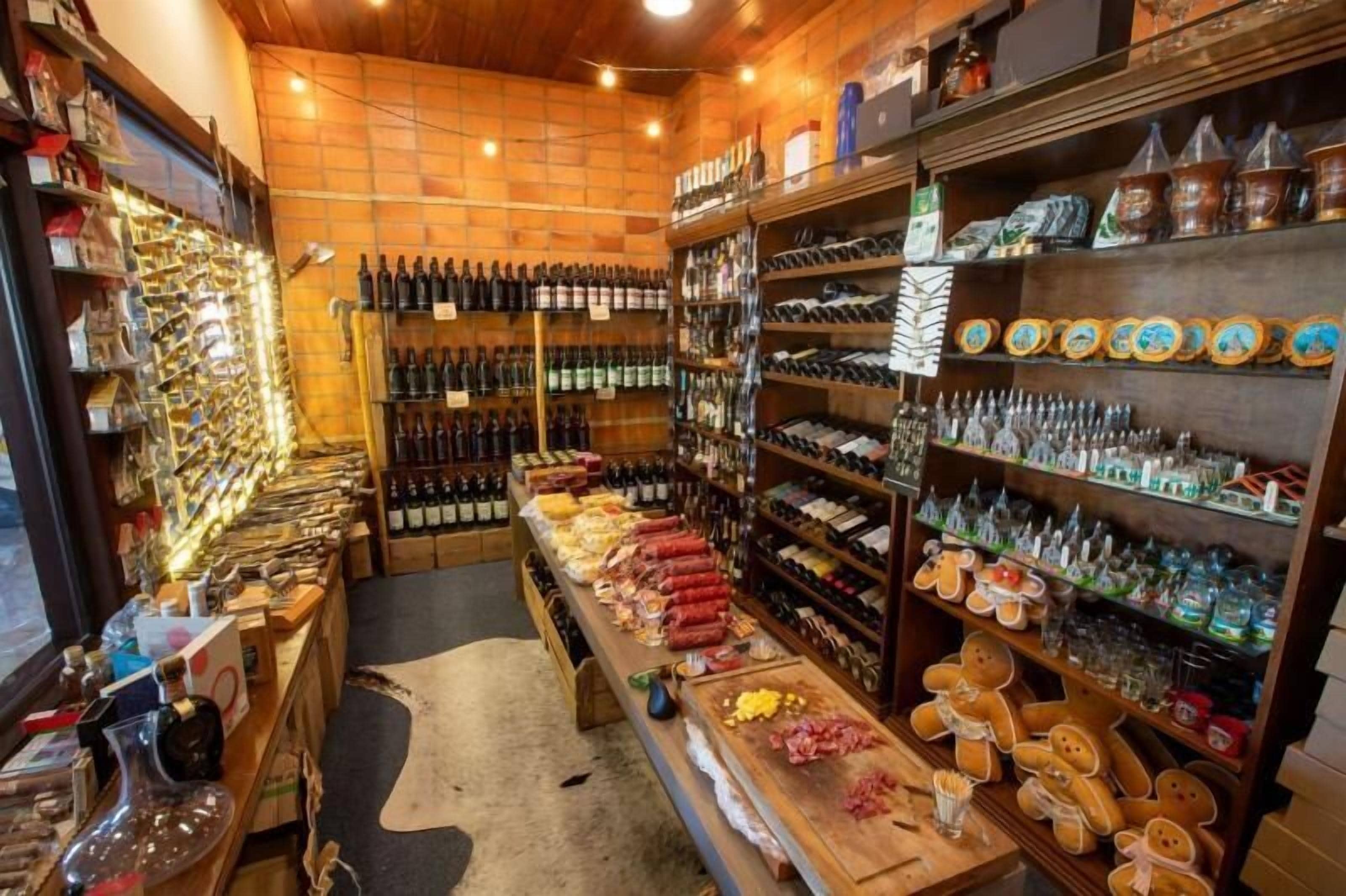 A store with shelves of wine bottles, cheese, and other food items.
